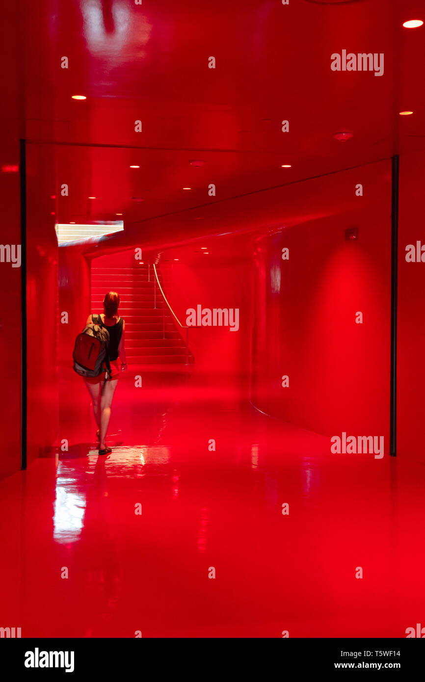A young woman walking in the red room of Seattle public library, the world's most beautiful library according to instagram done by Wordery in 2018. Stock Photo