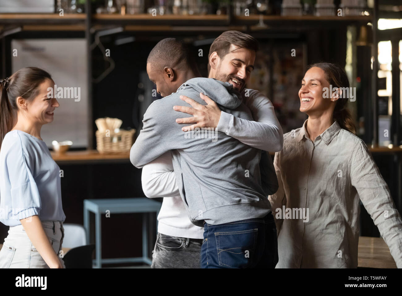 Diverse guys best friends hugging greeting each other at meeting Stock Photo