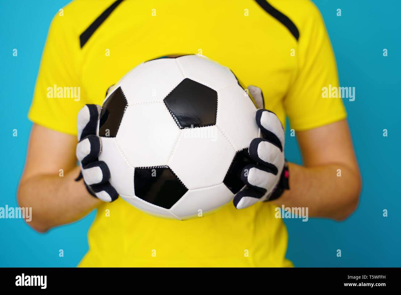 Man is socccer fan in yellow t-shirt with soccer ball Stock Photo