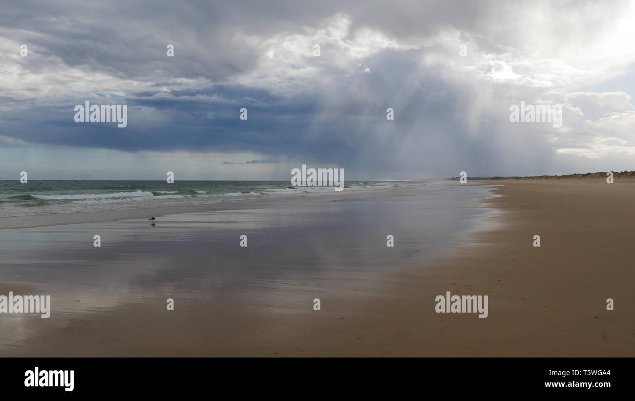 Sun, clouds and gusty wind on the beach of Praia Verde Stock Photo