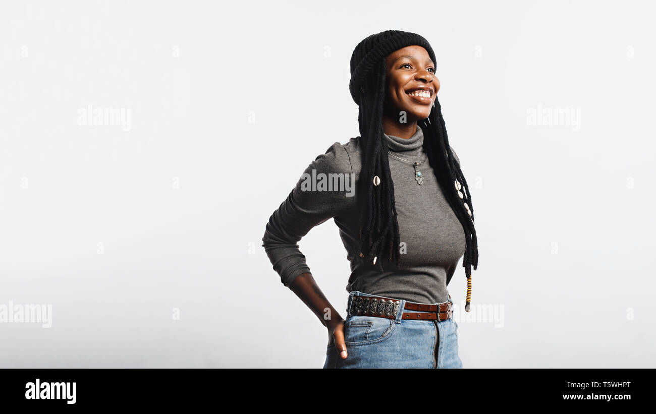 Portrait of cheerful african female in jeans and tshirt having long dreadlocks with cowrie shells. Smiling african woman isolated on white background. Stock Photo