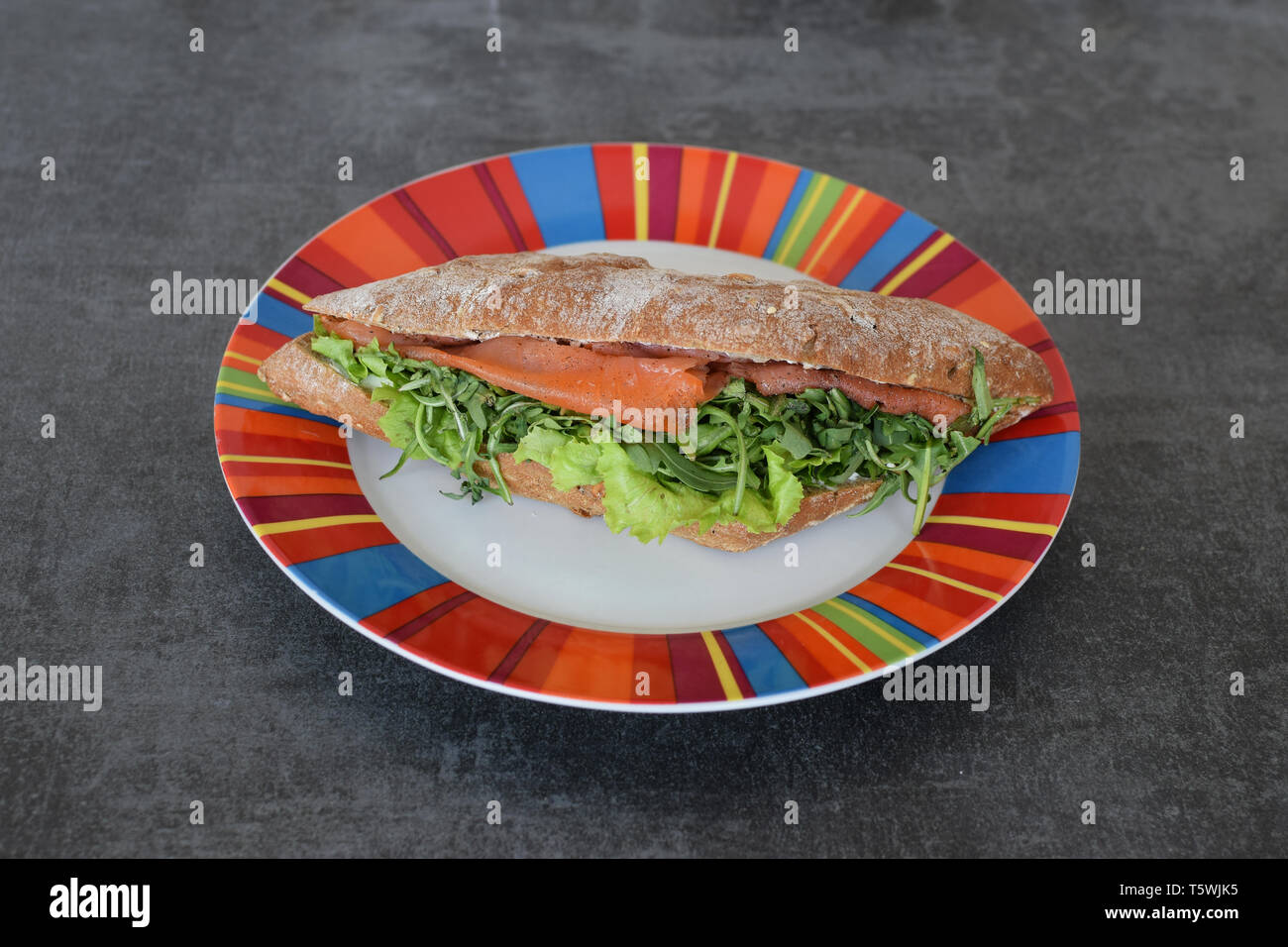 Smoked salmon baguette sandwich with arugula rocket green salad. Stock Photo