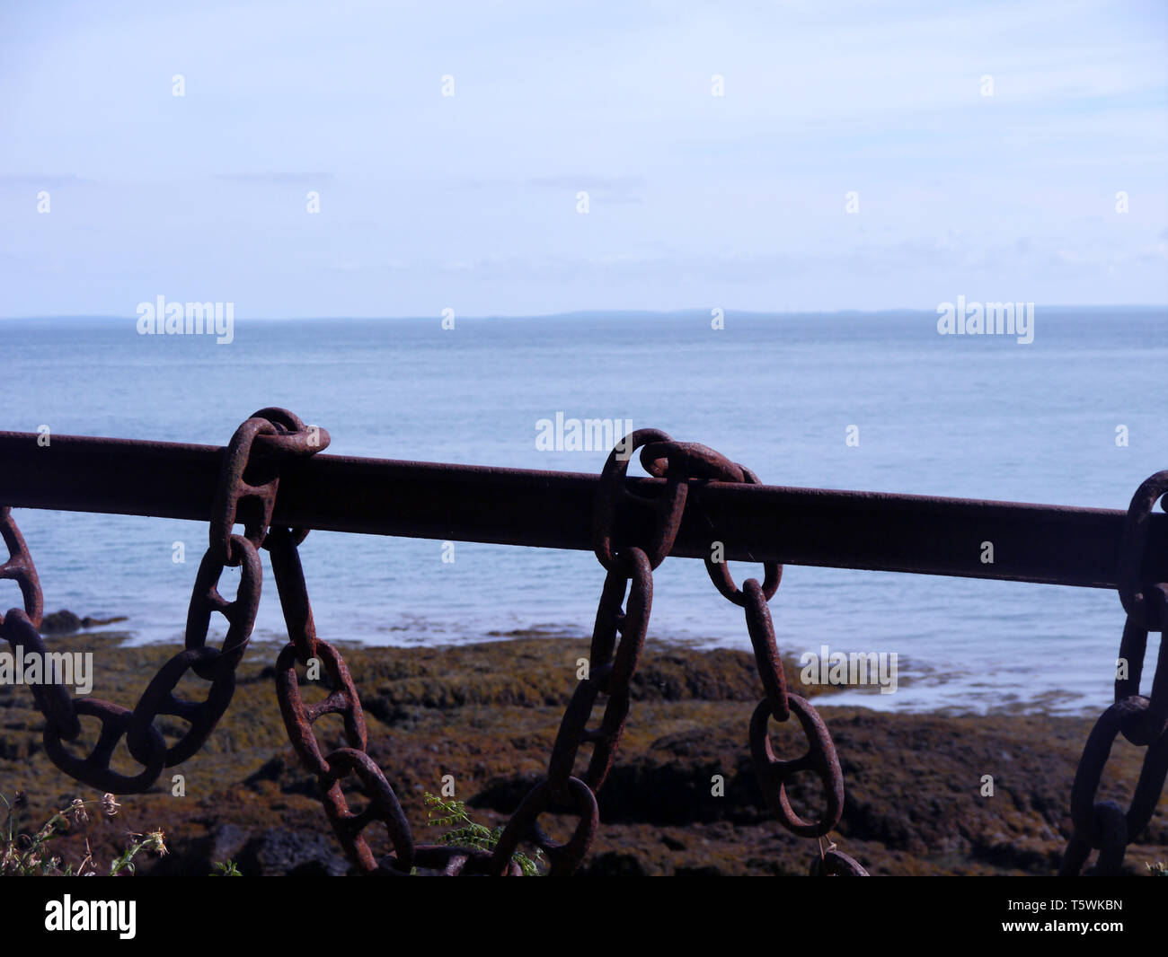 A Novel Old Rusty Iron Chain Link Fence Outside the Restored Fortress at Fliquet Bay on the Island of Jersey, Channel Isles, UK. Stock Photo