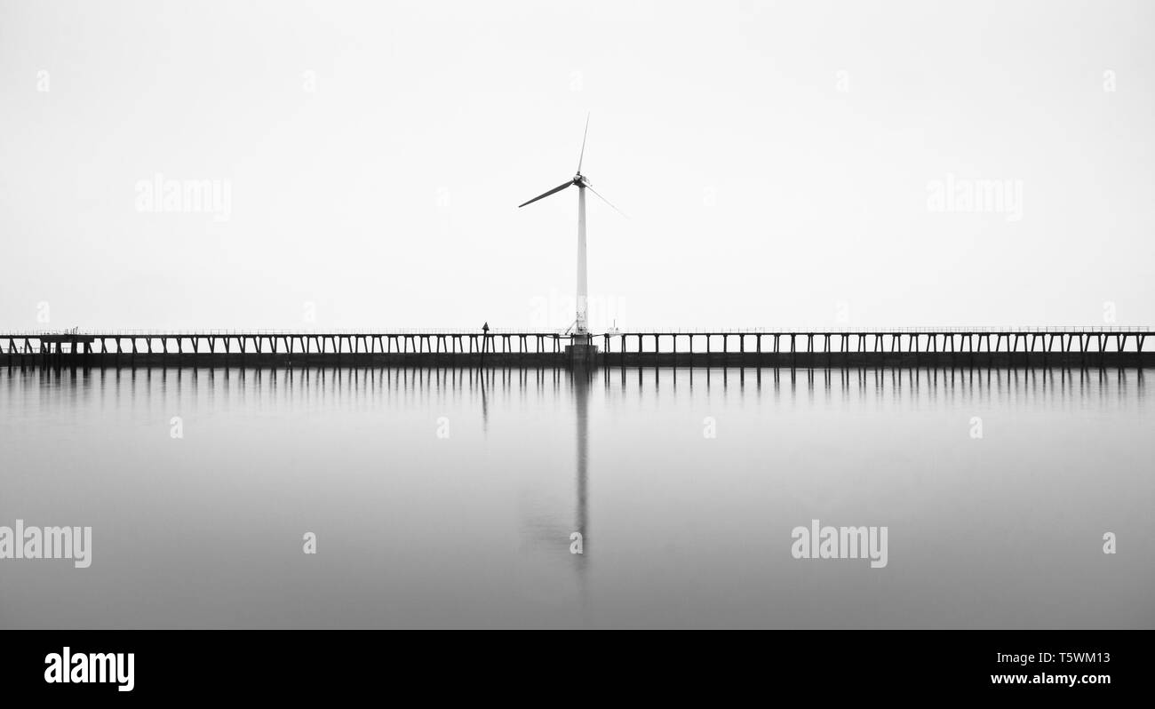 No sunrise on this morning at Blyth pier, but the coastline was surrounded by thick fog which made for some atmospheric looking B&W on Wind turbines Stock Photo