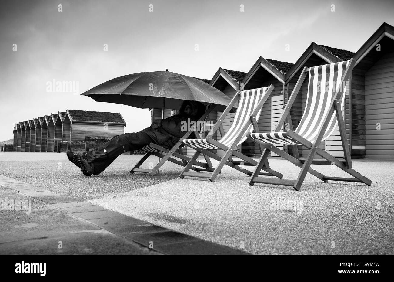 No sunrise this morning at Blyth beach huts, the coastline was surrounded by fog & rain, this didn't stop locals out with their deck chairs & umbrella Stock Photo