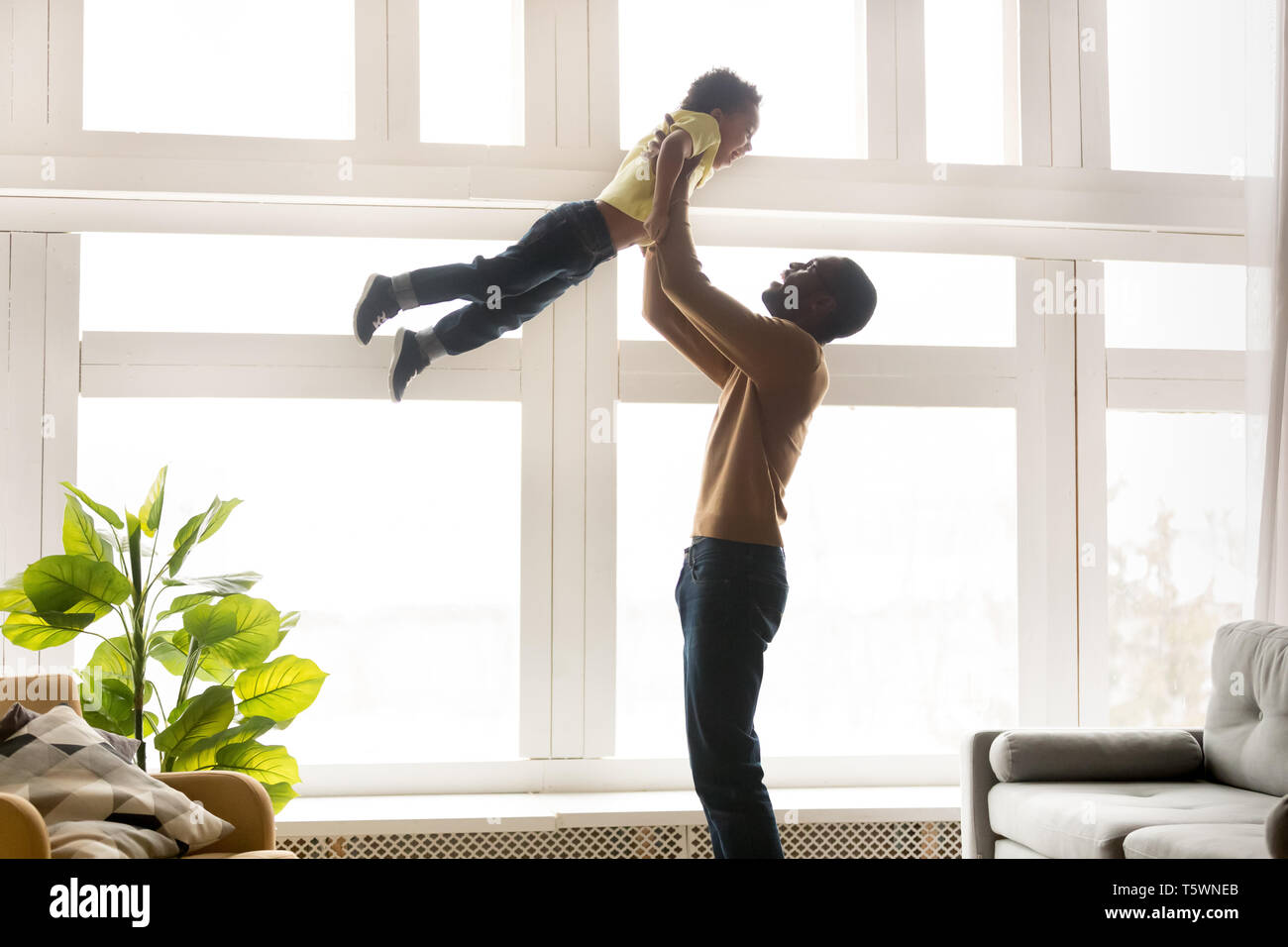 Happy african father lifting up in air little son Stock Photo