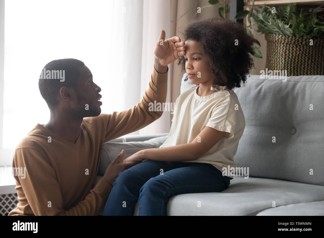 Worried father touch forehead of unhealthy daughter sitting on sofa ...