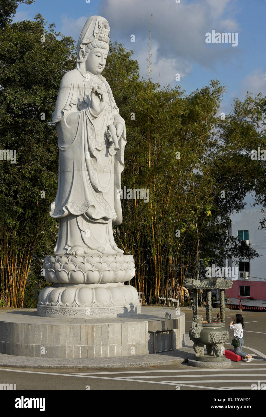 Woman praying at statue of Kwan Yin (Guan Yin), Goddess of Mercy, Puh Toh Tze (Poh Toh Tse, Pu Tuo Si) Buddhist temple, Kota Kinabalu, Sabah (Borneo), Stock Photo