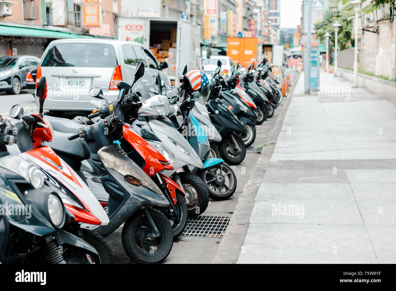 Row of motorcycle (motorbike) parking on the side of a street beside sidewalk of a street in