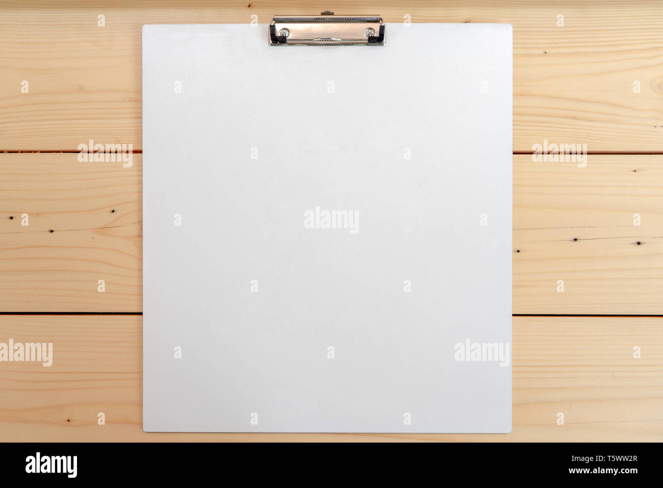 white empty plastic clipboard lay on the wood table. Stock Photo