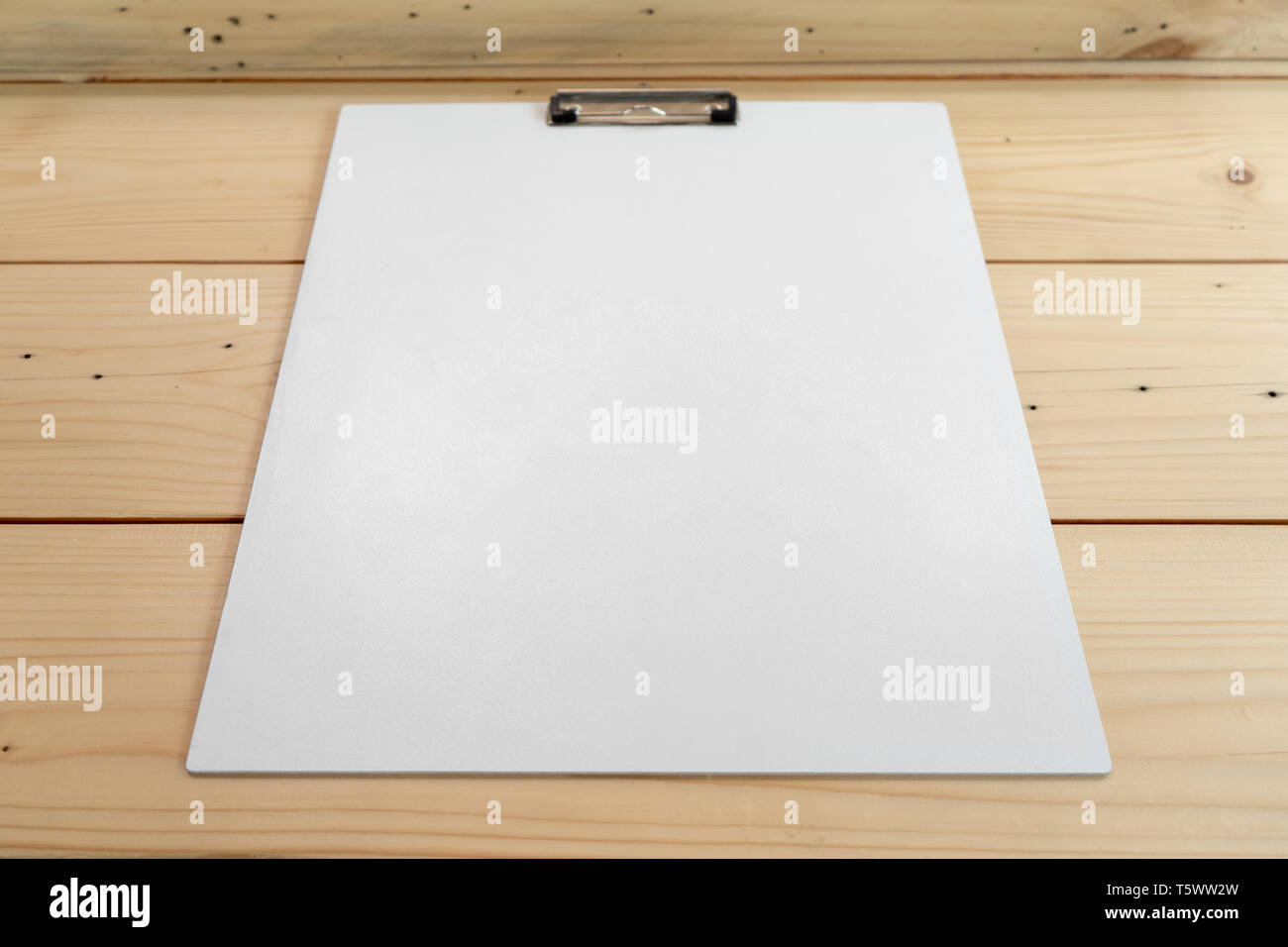 white empty plastic clipboard lay on the wood table. Stock Photo