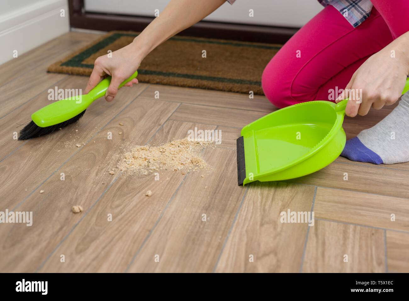 Closeup of woman cleaning floor with broom and dust pan Stock Photo