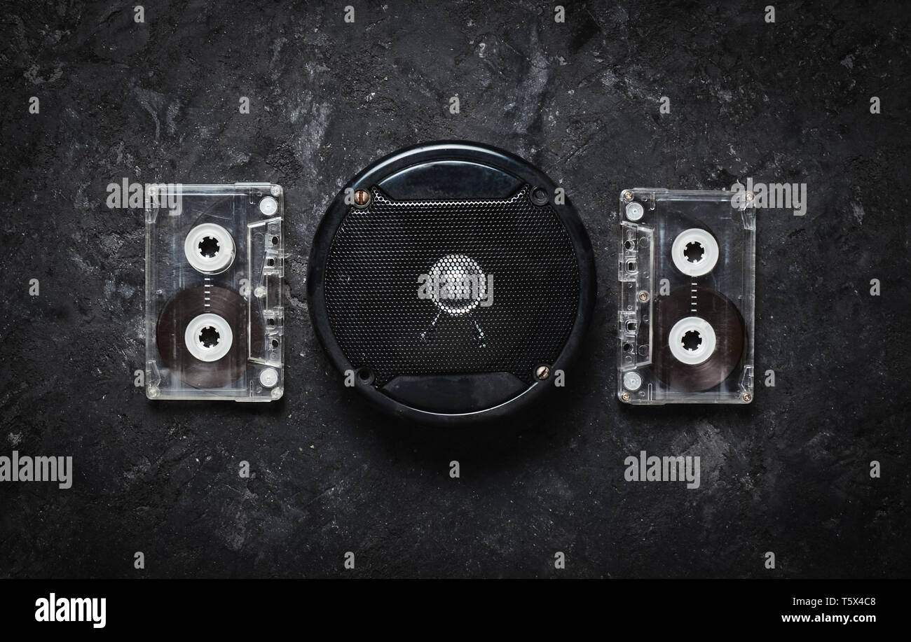 Acoustic speaker and audio cassette on a black concrete table. Retro technology. Meloman. Top view. Flat lay. Stock Photo