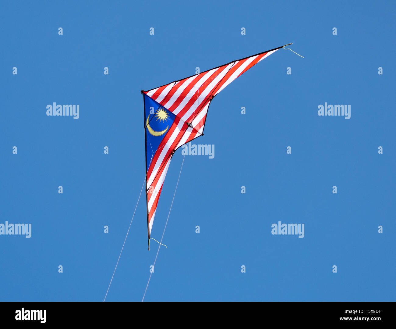 2-line stunt kite with the colours of the Malaysian flag flying on a blue sky background. Stock Photo