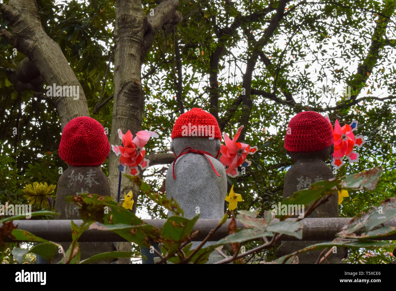 Three Ojizosama statues in Tokyo, Japan, wearing bright red knitted