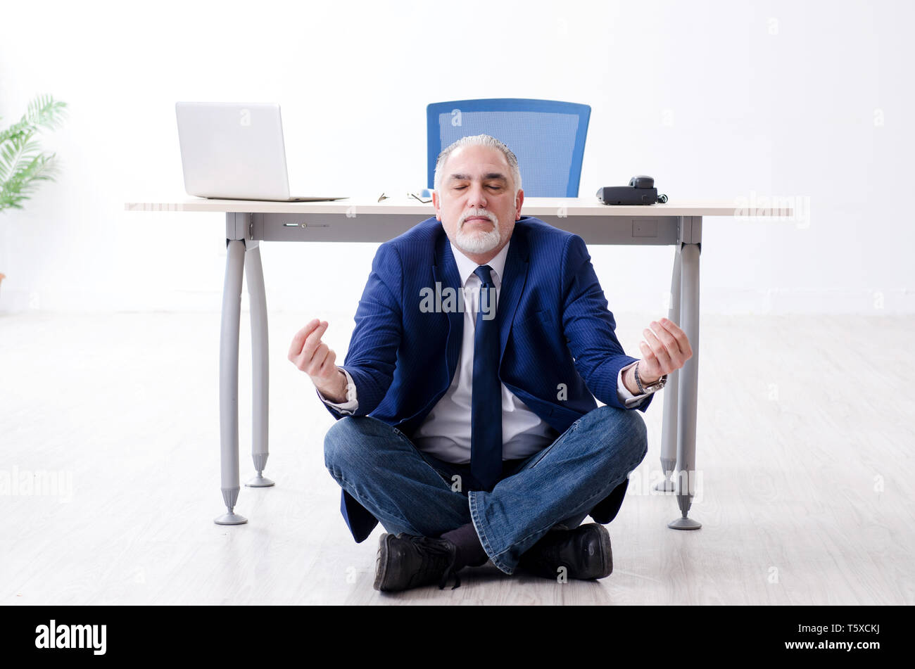 Aged businessman doing yoga exercises in the office Stock Photo - Alamy