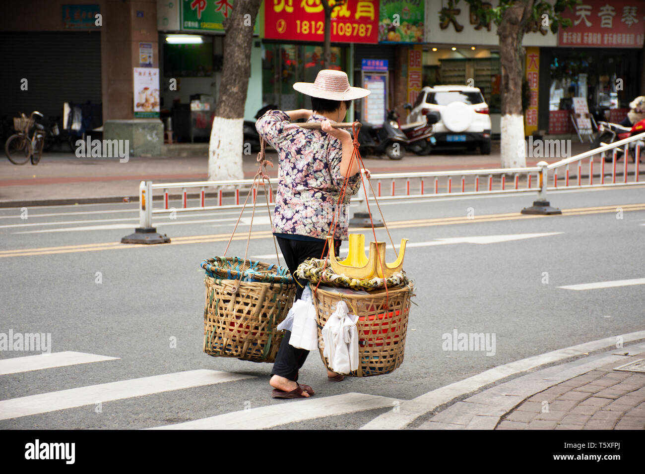 Old chinese woman people street vendors bearing hawker basket walking on beside road and traffic at Shantou downtown or Swatow city on May 9, 2018 in  Stock Photo