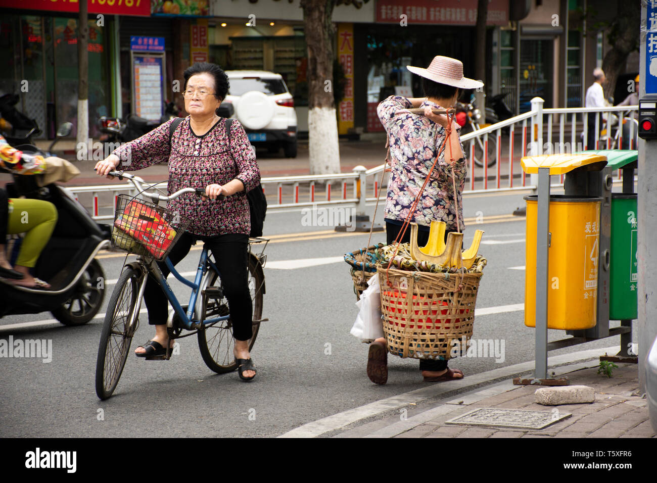 Old chinese woman people street vendors bearing hawker basket walking on beside road and traffic at Shantou downtown or Swatow city on May 9, 2018 in  Stock Photo