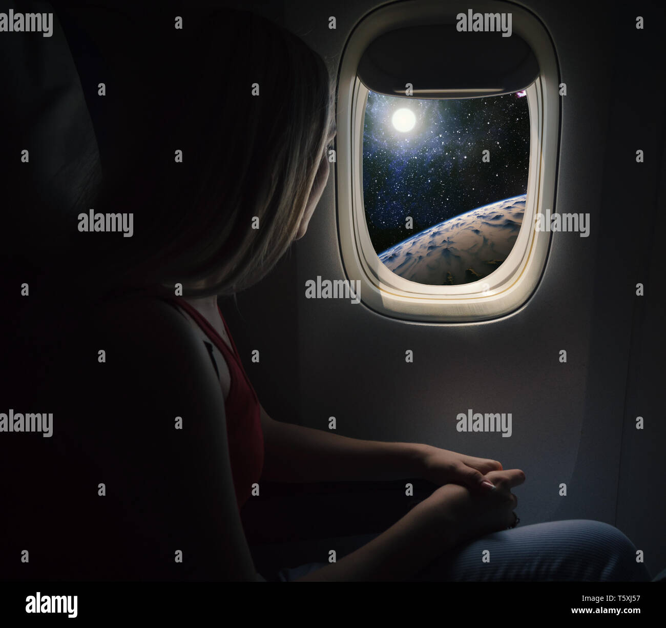 Woman in spaceship looks out the porthole. Commercial space travel concept. Stock Photo