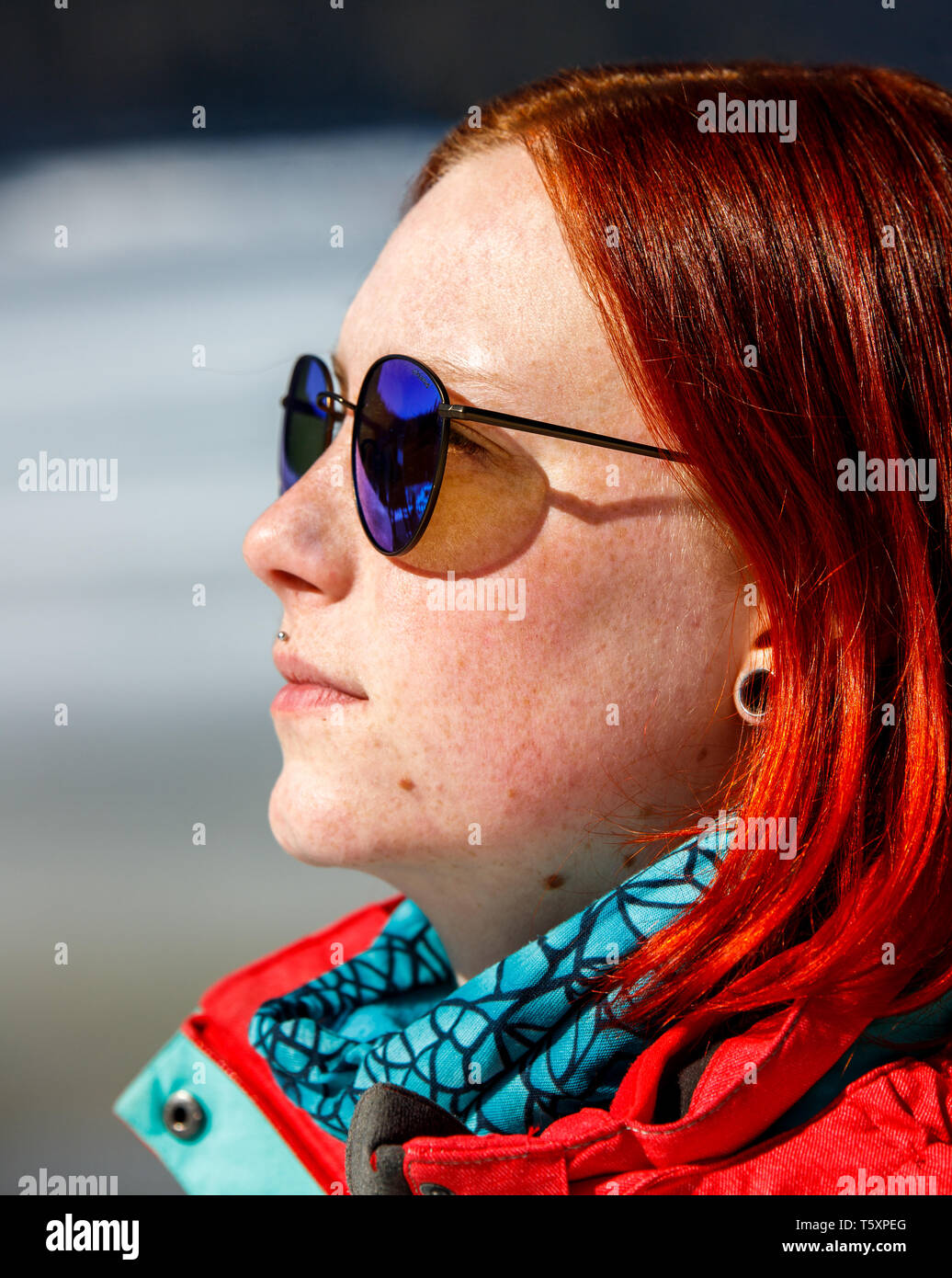 young red head girl with reflecting blue sunglasses out on a sunny winter day Stock Photo