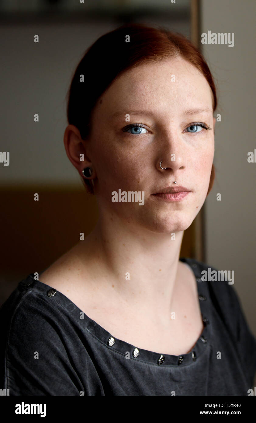 young pretty ginger girl with blue eyes looking sorrowful out of the window Stock Photo