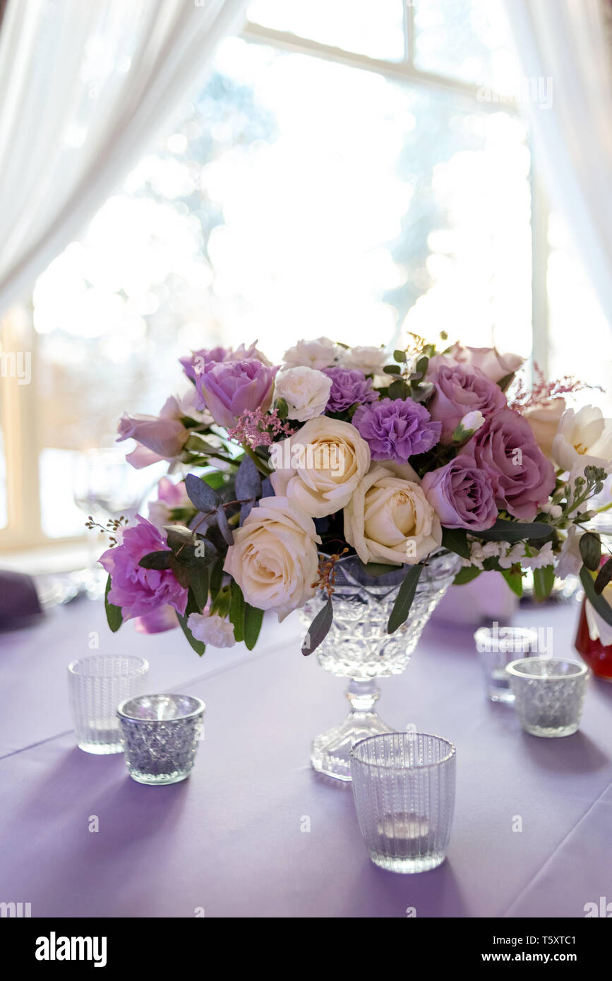 Beautiful bouquet in a crystal vase on a table. Fresh flowers and candles decorate a holiday table Stock Photo