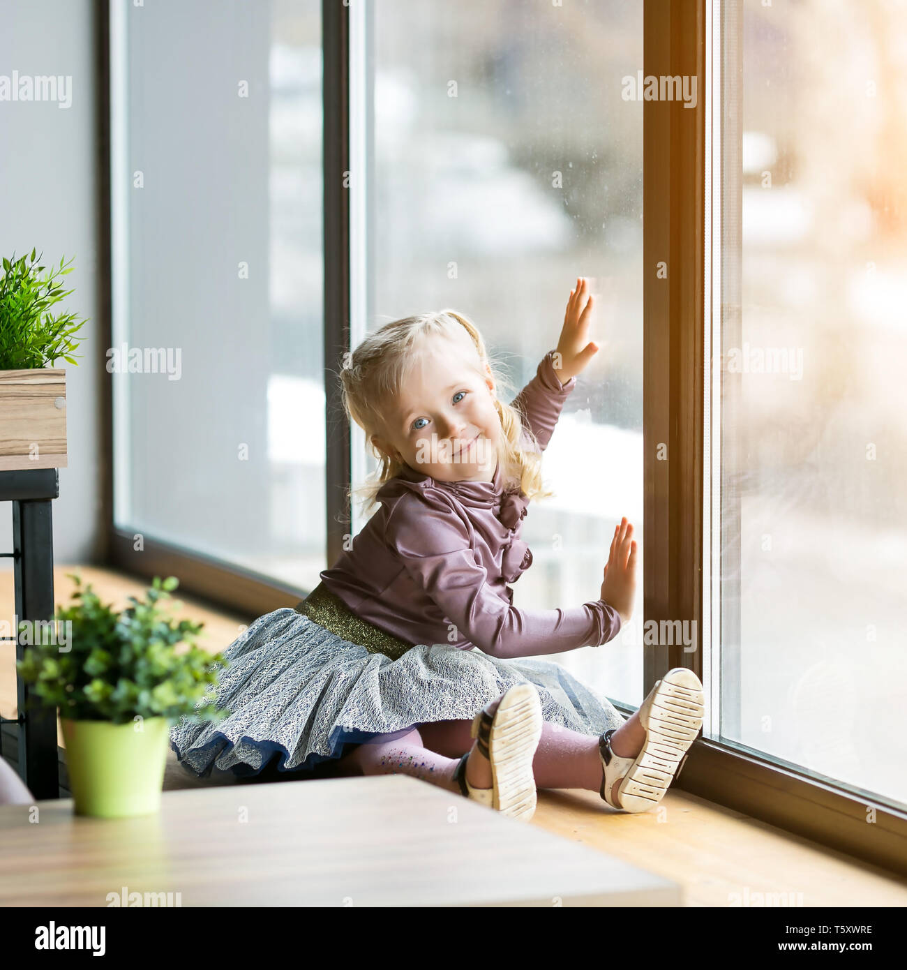 A Little Girl 4 5 Years Old Is Sitting On The Windowsill Of A