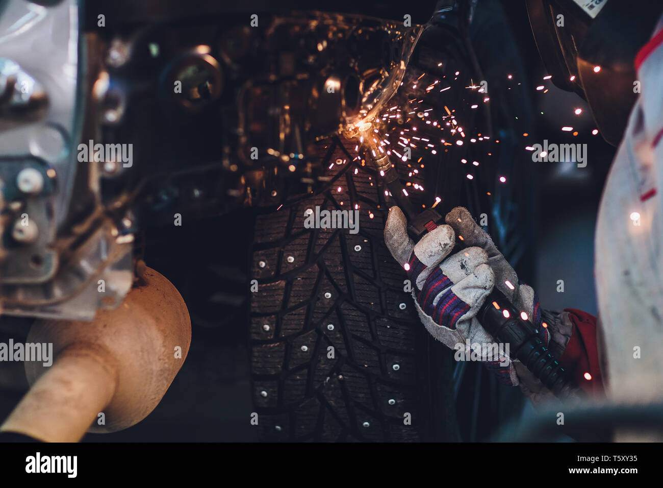professional repairman worker in automotive industry welding metal body car with sparks. Stock Photo