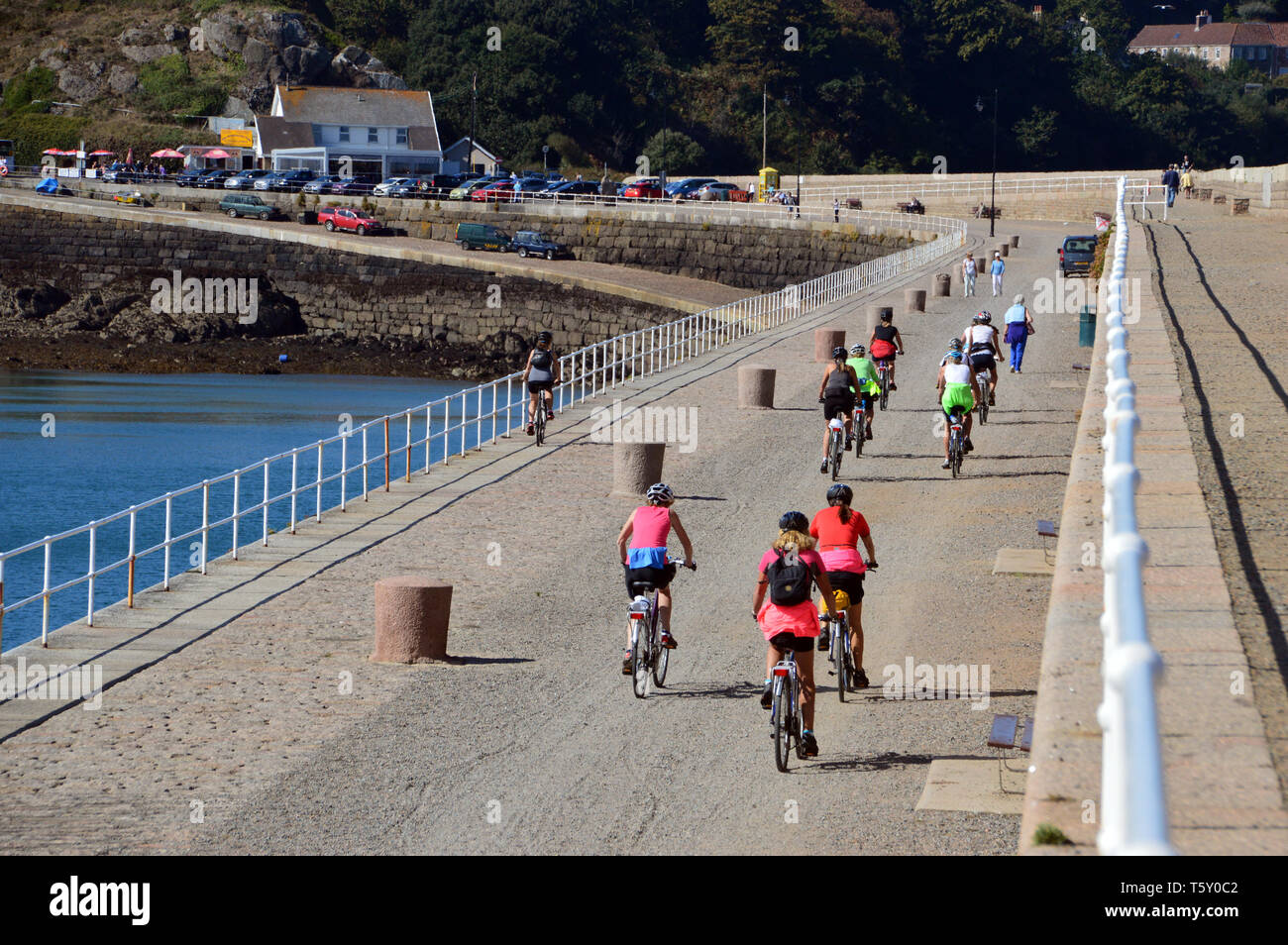 Women Cycling on  the 'Verclut' Break Water in St Catherine's Bay on the Island of Jersey, Channel Isles, UK bicycles Stock Photo