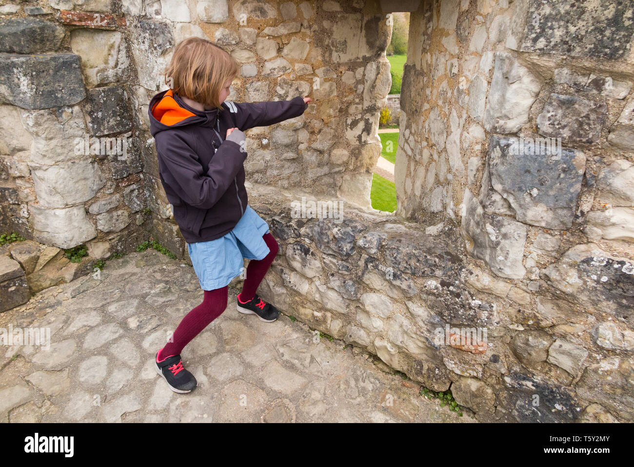 Child / kid / poses with arrow slit / arrow loop / arrow hole / in the defensive Shell Keep walls of Farnham castle, Farnham. Surrey, England. UK (108 Stock Photo