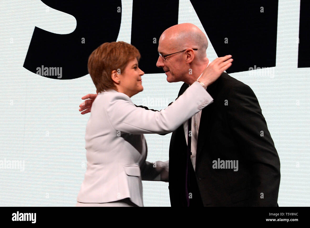 Edinburgh, Scotland, United Kingdom, 27, April, 2019. First Minister Nicola Sturgeon embraces Scottish Education Secretary and Deputy First Minister John Swinney after his speech to the Scottish National Party's Spring Conference in the Edinburgh International Conference Centre. © Ken Jack / Alamy Live News Stock Photo