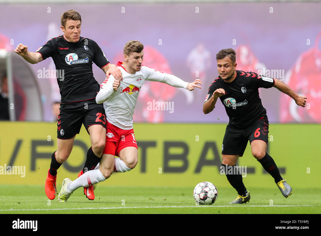 Leipzig, Germany. 27th Apr, 2019. Soccer: Bundesliga, 31st matchday, RB Leipzig - SC Freiburg in der Red-Bull-Arena Leipzig. Leipzig's Timo Werner (M) is stopped rudely by Freiburg's Dominique Heintz (l). Amir Abrashi of Freiburg on the right. Credit: Jan Woitas/dpa-Zentralbild/dpa - IMPORTANT NOTE: In accordance with the requirements of the DFL Deutsche Fußball Liga or the DFB Deutscher Fußball-Bund, it is prohibited to use or have used photographs taken in the stadium and/or the match in the form of sequence images and/or video-like photo sequences./dpa/Alamy Live News Stock Photo