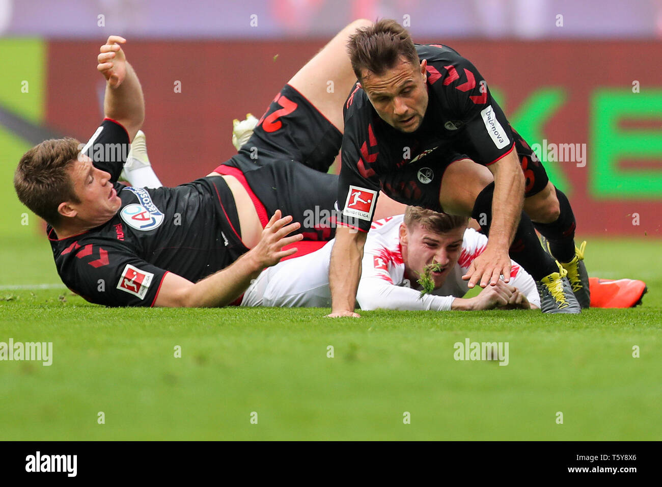 Leipzig, Germany. 27th Apr, 2019. Soccer: Bundesliga, 31st matchday, RB Leipzig - SC Freiburg in der Red-Bull-Arena Leipzig. Leipzig's Timo Werner (M) is stopped rudely by Freiburg's Dominique Heintz (l) and Amir Abrashi. Credit: Jan Woitas/dpa-Zentralbild/dpa - IMPORTANT NOTE: In accordance with the requirements of the DFL Deutsche Fußball Liga or the DFB Deutscher Fußball-Bund, it is prohibited to use or have used photographs taken in the stadium and/or the match in the form of sequence images and/or video-like photo sequences./dpa/Alamy Live News Stock Photo
