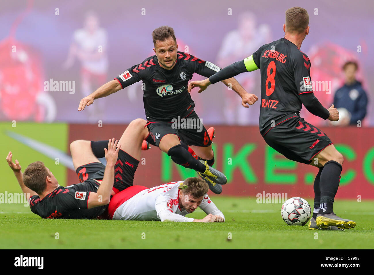 Leipzig, Germany. 27th Apr, 2019. Soccer: Bundesliga, 31st matchday, RB Leipzig - SC Freiburg in der Red-Bull-Arena Leipzig. Leipzig's Timo Werner (M) is stopped rudely by Freiburg's Dominique Heintz (l) and Freiburg's Amir Abrashi (r). Mike Frantz on the right. Credit: Jan Woitas/dpa-Zentralbild/dpa - IMPORTANT NOTE: In accordance with the requirements of the DFL Deutsche Fußball Liga or the DFB Deutscher Fußball-Bund, it is prohibited to use or have used photographs taken in the stadium and/or the match in the form of sequence images and/or video-like photo sequences./dpa/Alamy Live News Stock Photo