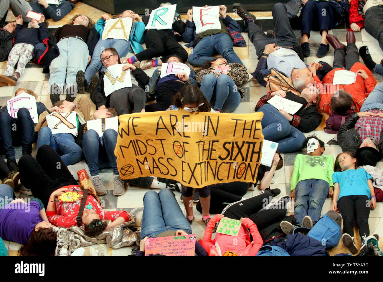 Glasgow, Scotland, UK 27th April, 2019. Kelvingrove Art Galleries and Museum saw a copycat protest at climate change to the blue whale in London as dippy the Diplodocus saw an Extinction Rebellion Climate change protesters lie down protest ie “die- in” through earth being poisoned. Gerard Ferry/Alamy Live News Stock Photo