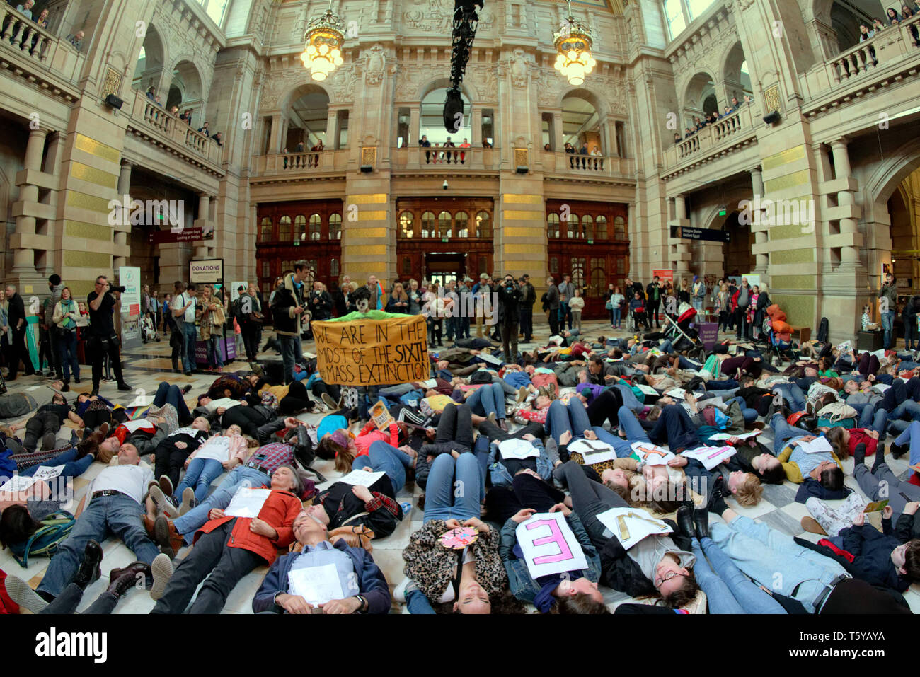 Glasgow, Scotland, UK 27th April, 2019. Kelvingrove Art Galleries and Museum saw a copycat protest at climate change to the blue whale in London as dippy the Diplodocus saw an Extinction Rebellion Climate change protesters lie down protest ie “die- in” through earth being poisoned. Gerard Ferry/Alamy Live News Stock Photo