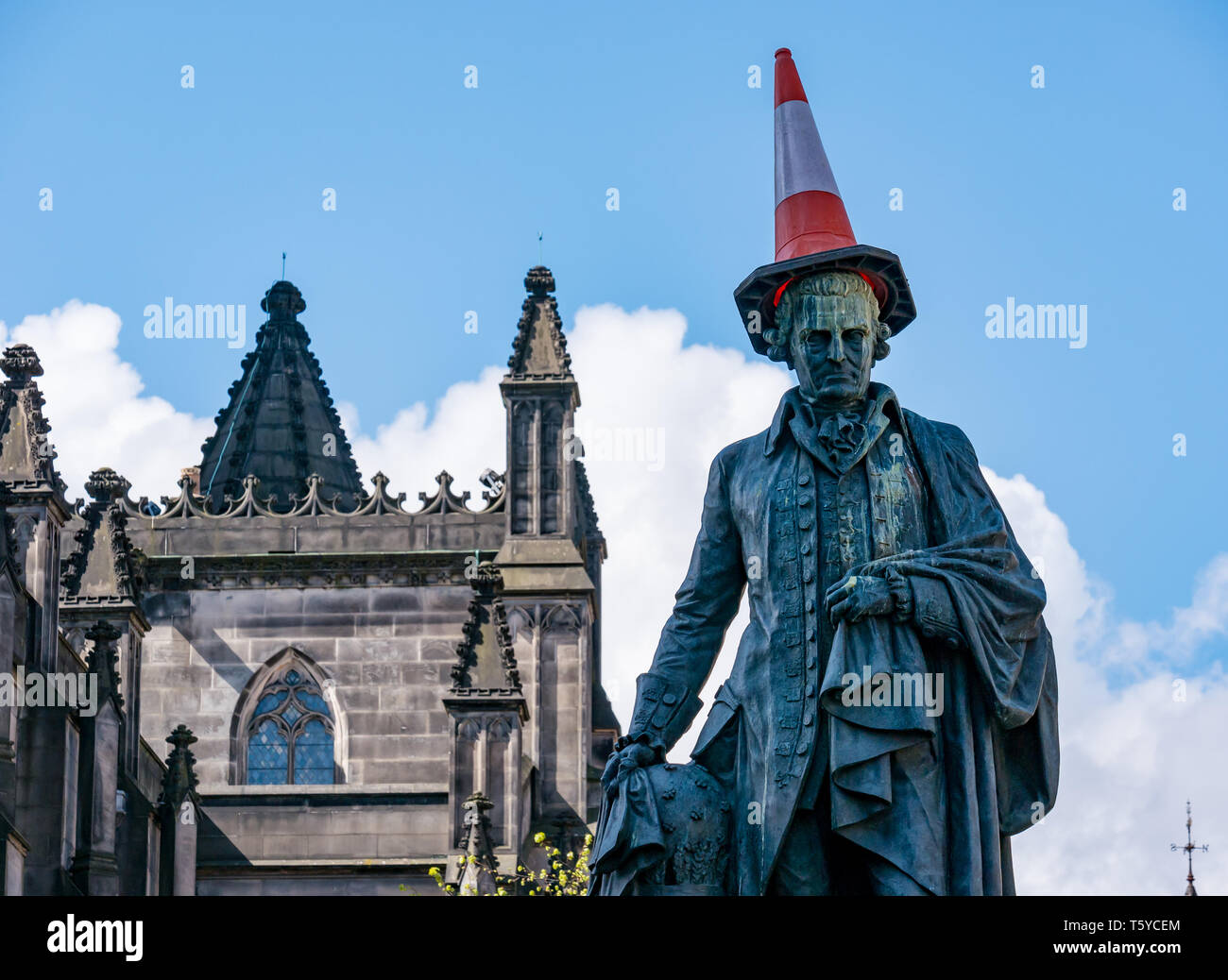 Royal Mile, Edinburgh, Scotland, United Kingdom, 27th April 2019.  Revellers decorate the Adam Smith statue with traffic cone in Spring sunshine as he looks down on the tourists passing by Stock Photo