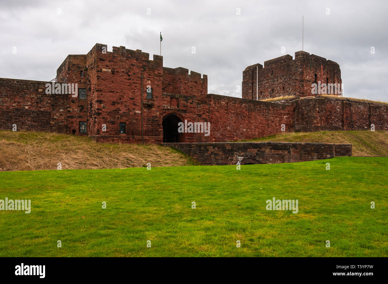 Under a greyish cloudy sky the square four-storey red sandstone keep  peers over the outer gatehouse and curtain wall, dominating the castle's skyline Stock Photo
