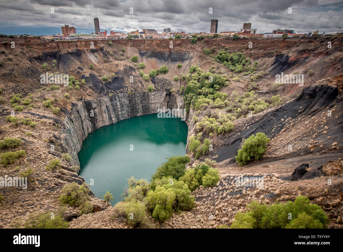Wide view of The Big Hole in Kimberley, a result of the mining industry, with the town skyline on the edge Stock Photo
