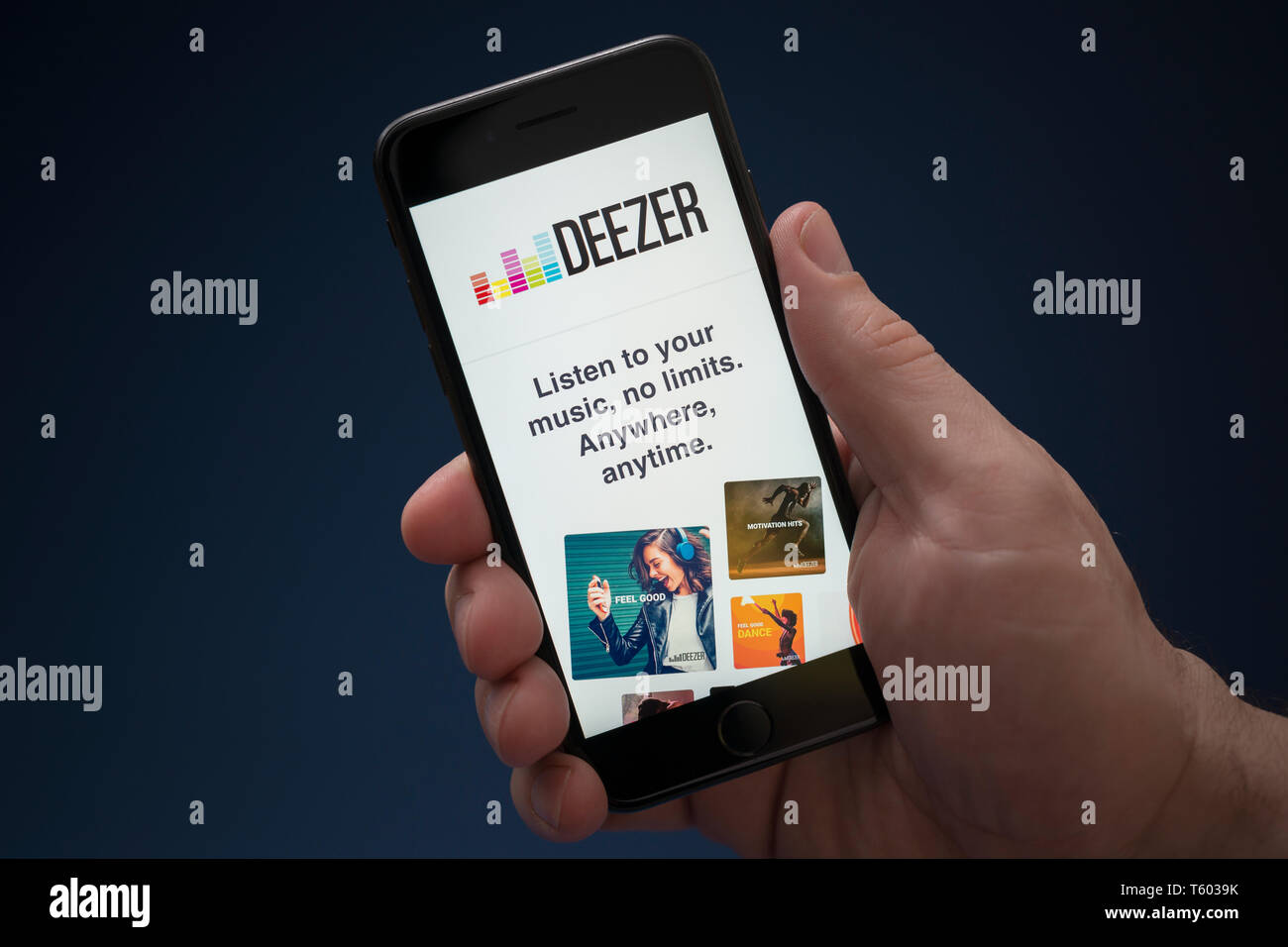 A man looks at his iPhone which displays the Deezer logo (Editorial use only). Stock Photo