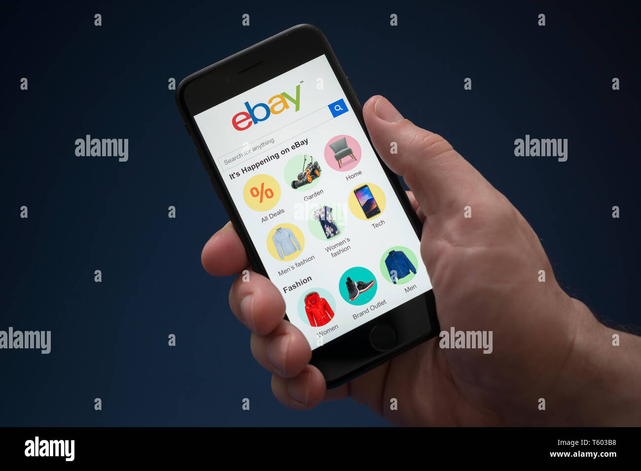 A man looks at his iPhone which displays the ebay logo (Editorial use only). Stock Photo