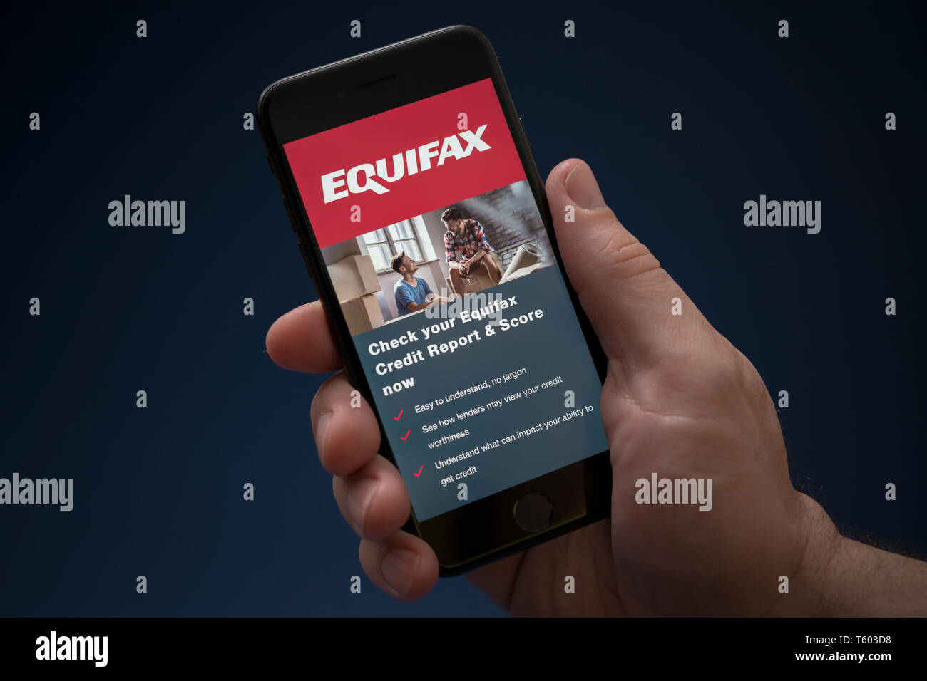 A man looks at his iPhone which displays the Equifax logo (Editorial