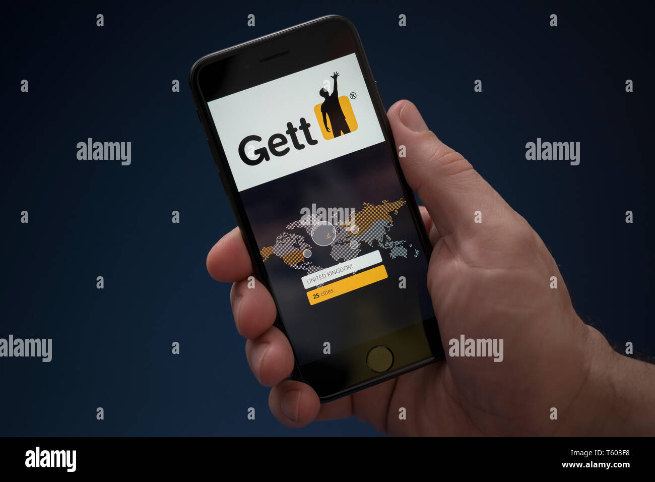 A man looks at his iPhone which displays the Gett logo (Editorial use only). Stock Photo