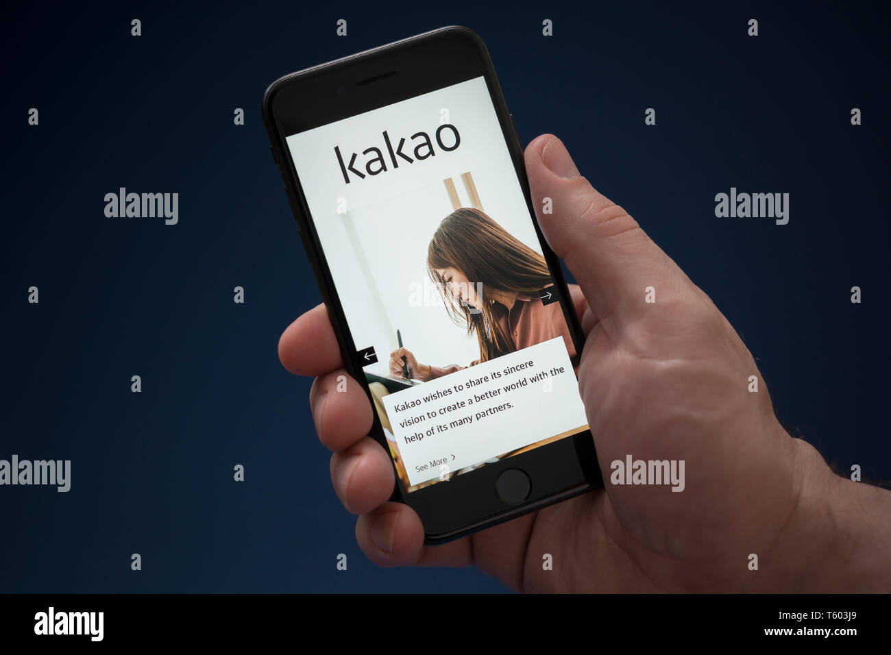 A man looks at his iPhone which displays the Kakao logo (Editorial use only). Stock Photo