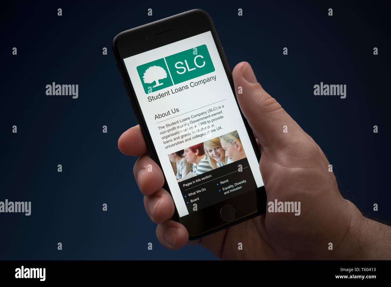 A man looks at his iPhone which displays the Student Loans Company logo (Editorial use only). Stock Photo