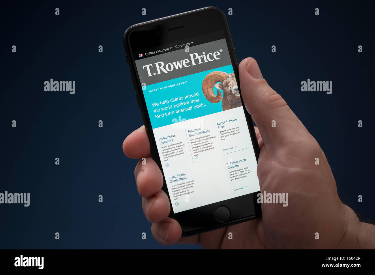 A man looks at his iPhone which displays the T.Rowe Price logo (Editorial use only). Stock Photo