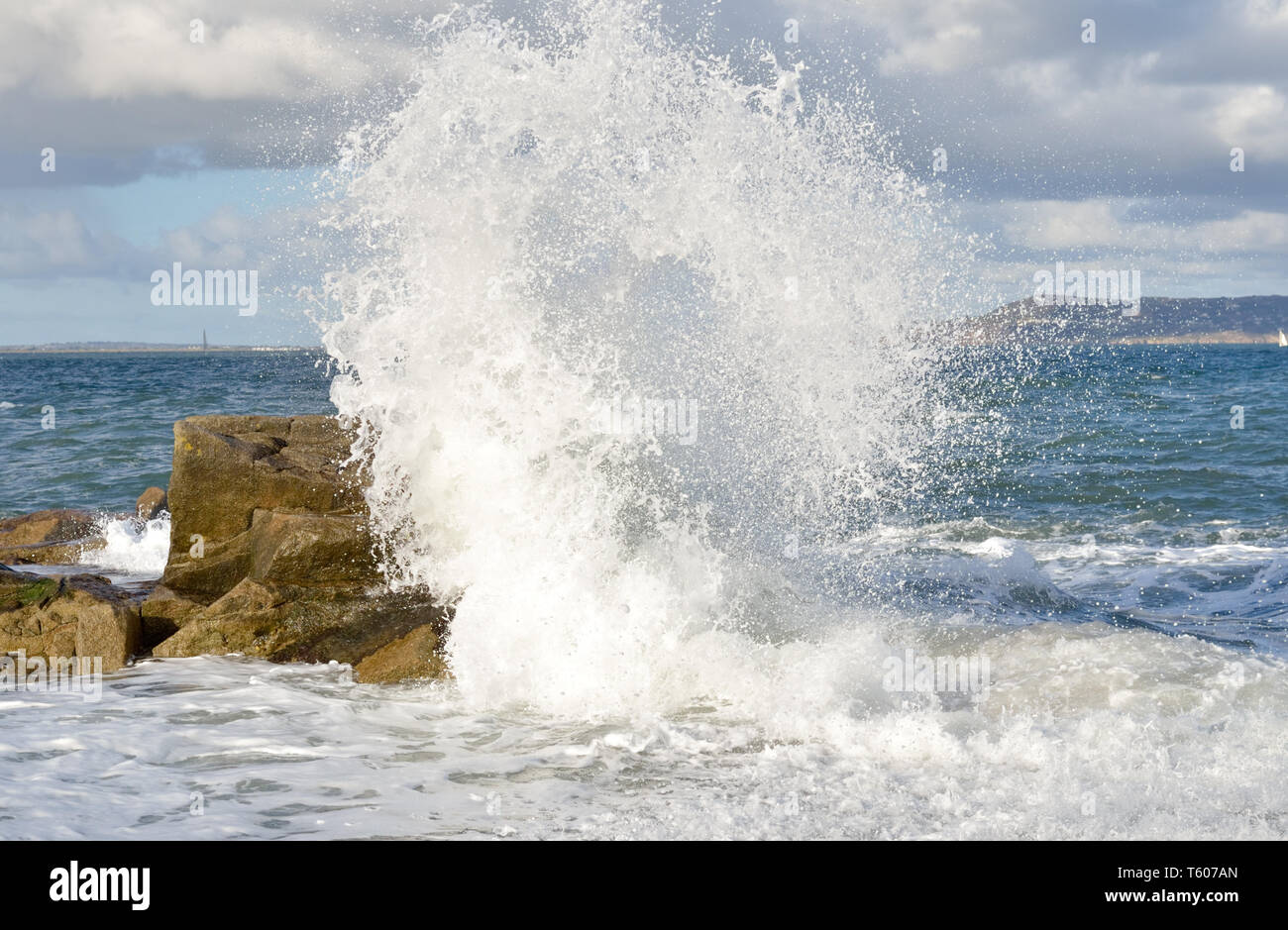 Power of nature.Waves impact onto rocks driven by onshore winds creating a dispersion of water spray. Stock Photo