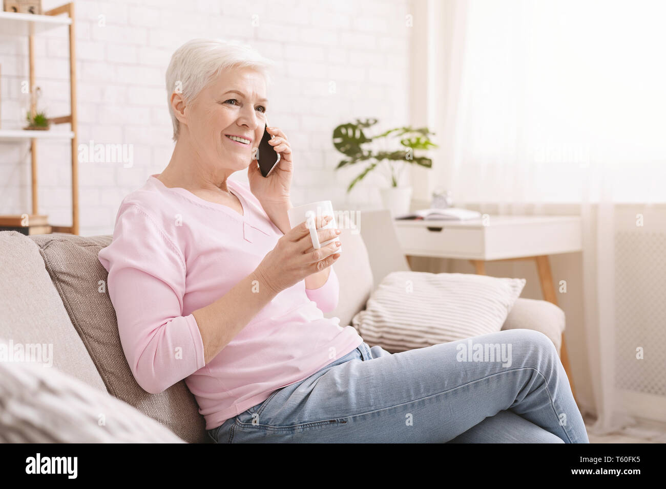 Cheerful senior lady having phone call on her smartphone Stock Photo