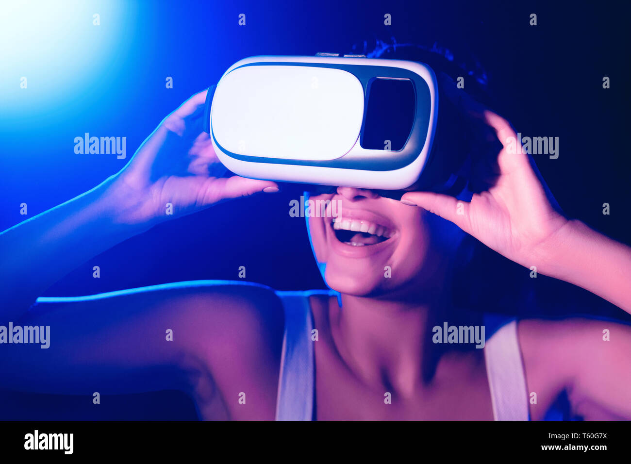 Girl using VR goggles in colorful neon lights, having fun Stock Photo