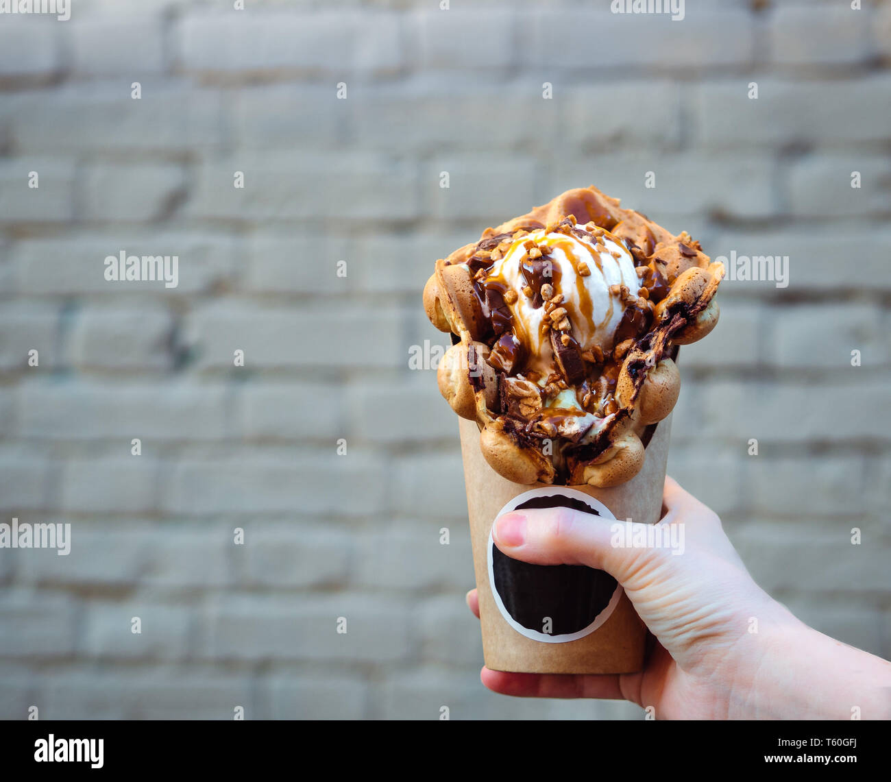 Hong Kong waffles in female hand on brick wall background. Delicious bubble  waffle with ice cream and caramel syrup in woman hand. Trendy food. Copy  space for text Stock Photo - Alamy